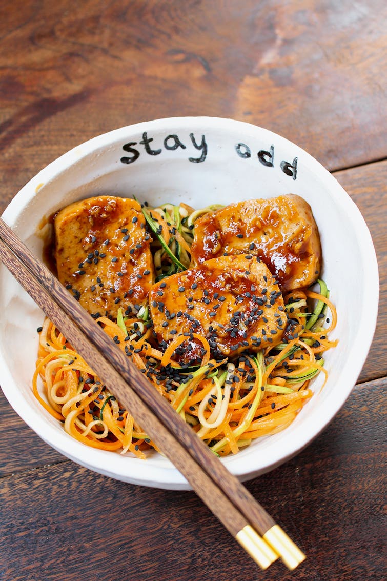 hoisin tofu with a courgette noodle slaw in a white bowl with chopsticks 