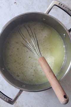 The garlic soup in the pot with a whisk sticking out of it. 