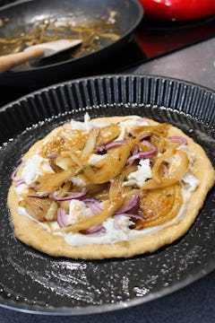 The flatbread with its toppings on an oiled baking tray. 