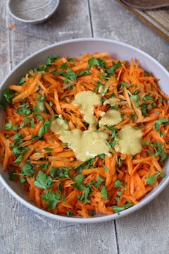 vinaigrette on top of the grated carrots in mixing bowl 
