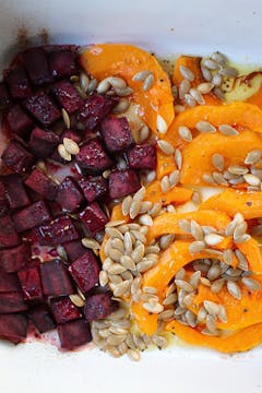pumpkin seeds on top of pumpkin and beetroot in a baking dish