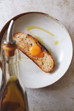 An egg yolk on top of a slice of bread, drizzled with olive oil. 