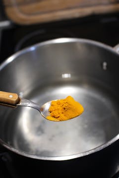 turmeric in teaspoon over saucepan 