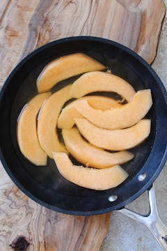 Melon slices in hot brine sitting in a pan. 