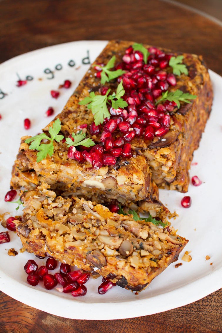 Butternut squash nut roast on a white plate, topped with pomegranate seeds