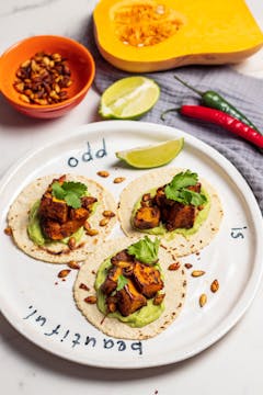 Three tacos with butternut squash filling served with slice of lime