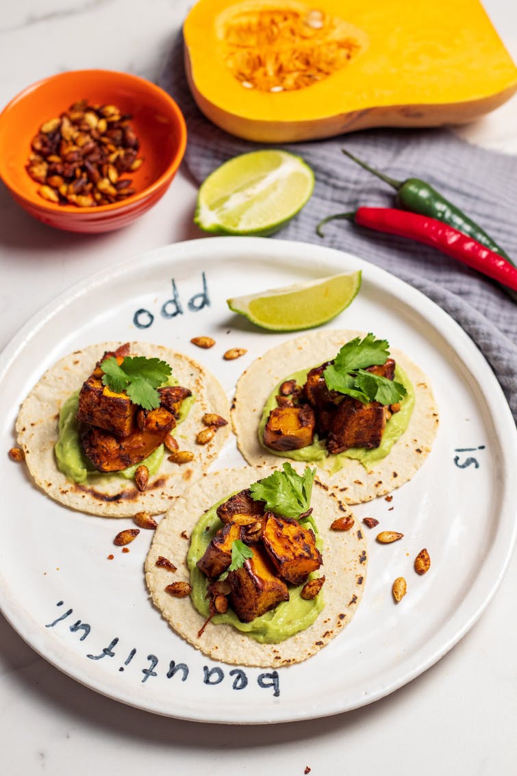 Three tacos with butternut squash filling served with slice of lime