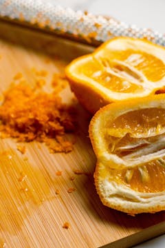 Seville oranges cut in half on a chopping board with grated zest next to them.