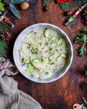 thin layer of potatoes at the bottom of the oven dish layered with sliced Brussel sprouts, shallot some black pepper and thyme leaves