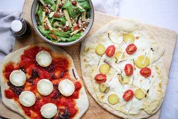 pizzas on a board with a side salad 