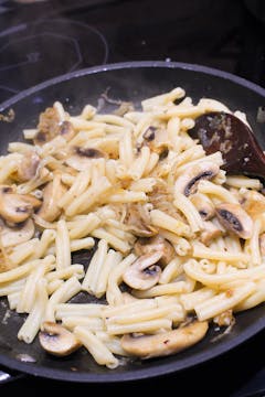 pasta, mushrooms and onion in frying pan 