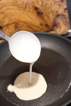 crepe batter being poured in frying pan