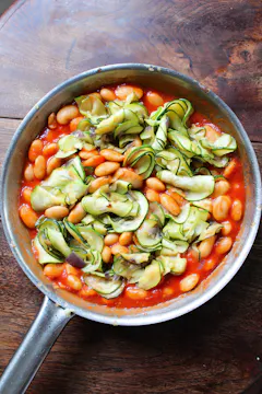 courgettes and butter beans in tomato sauce in metal pan