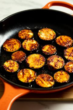 in a frying pan, marinated courgette getting cooked 