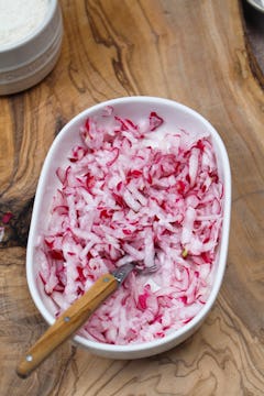 Grated radishes in bowl with a spoon 