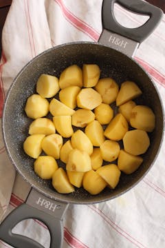 halved peeled potatoes on a sauce pan