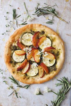 A Peach & Courgette Pizza, surrounded by sprigs of rosemary 
