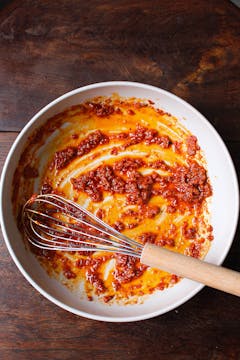 Harissa mixture in large mixing bowl with a whisk