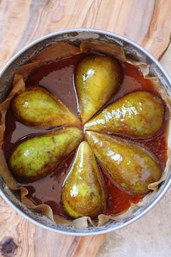 Pears laid cut side down in a tin of caramel. 