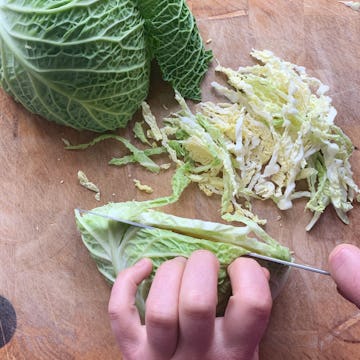 savoy cabbage cut in in half , then chopped finely side down with sharp knife