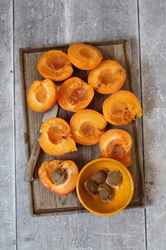 Halved apricot and their stones on the side in bowl 