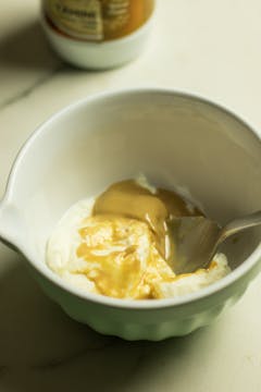 yoghurt, tahini, crushed garlic clove, olive oil in a bowl with a spon