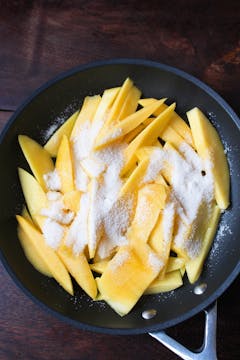 mango slices and sugar in pan
