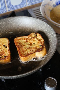 2 slices of french toast being fried on a frying pan