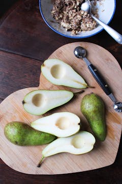 Pears cut in half on chopping board 