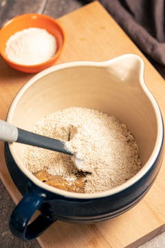 The wet and dry ingredients of date, tahini and oat cookies combined in a bowl.