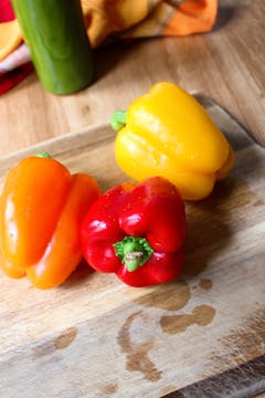 red, orange and yellow peppers on a cutting board