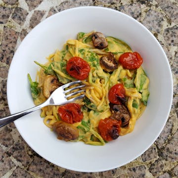 A plate of Creamy Sweet Potato Spaghetti with Roasted Veg, with a fork resting on top. 