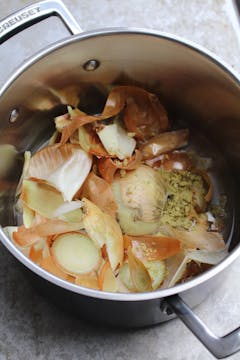 steel saucepan with onion peel and vegetable stock crushed 