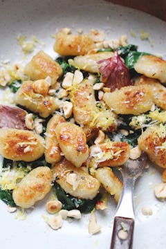 gnocchis served with wilted spinach, parmesan and toasted hazelnuts on a plate with fork