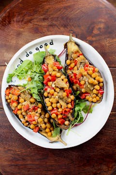 chickpea stuffed aubergines on a white plate with a wooden background