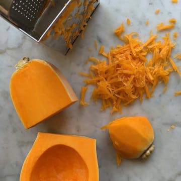 butternut squash in the process of being peeled and grated