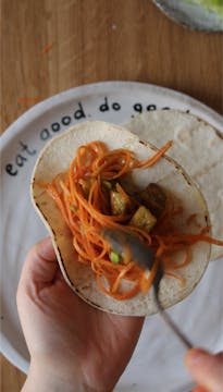 taco shells being filled with carrots, avocado and tofu