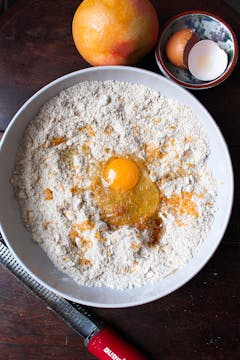 an egg being added to the dry ingredients for cookies