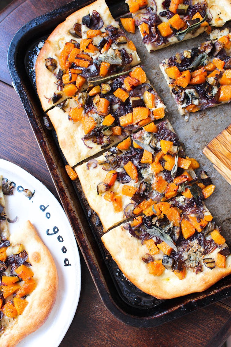 Roasted squash and aubergine pizza with caramelised onions on a baking tray