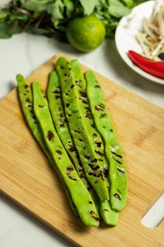 Blistered flat beans on a chopping board