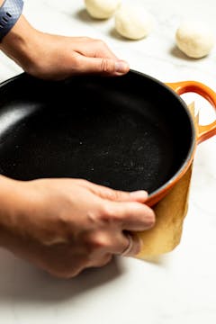 using a heavy rounded pan to press down on the dough to make tortilla 