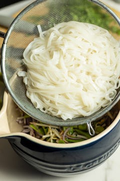 Prepared rice noodles in a sieve.