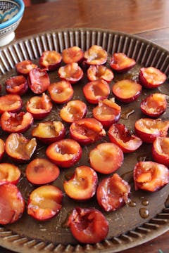 Plums drizzled with syrup on baking tray