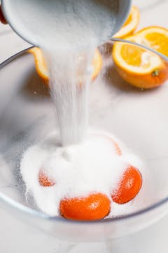 4 egg yolk in a bowl and caster sugar is pouring into the bowl with yolk