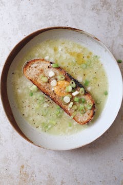A slice of toast in a bowl of garlic soup.