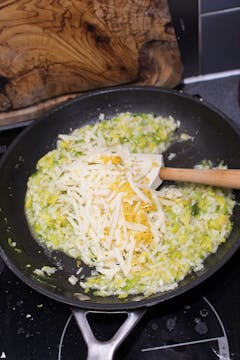 risotto cooking in frying pan with wooden spoon