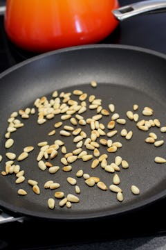 Pine nuts being toasted in a pan. 