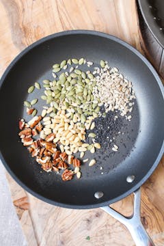 nuts and seeds being toasted in a frying pan