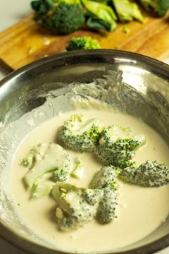 Pieces of broccoli in a bowl of batter. 