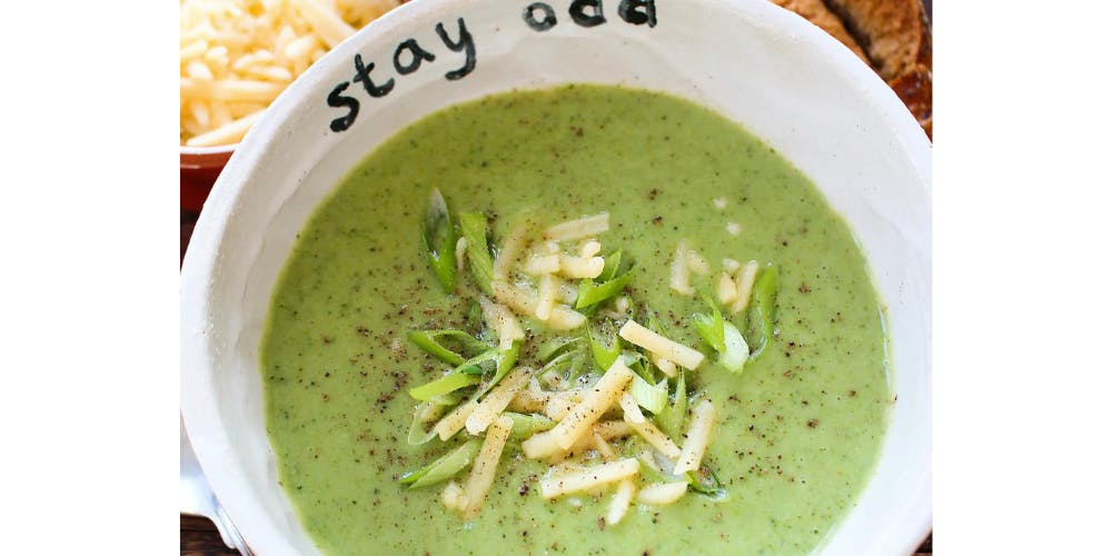 broccoli soup topped with mature cheddar in a white bowl